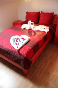 a red bed with two swans towels on it at Gargždų pramogos in Gargždai