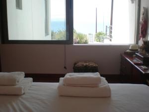 a bedroom with two towels on a bed with a window at Marvelous house by the sea in Vouliagmeni Lake