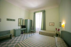 a bedroom with a bed and a desk and a window at Hotel Gran Bretagna Ortigia in Syracuse