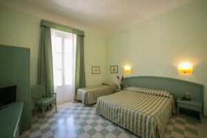 a hotel room with two beds and a window at Hotel Gran Bretagna Ortigia in Siracusa