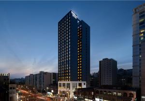 a tall building with lights on in a city at Shilla Stay Seocho Gangnam Station in Seoul