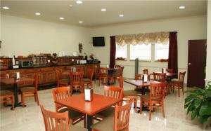 a restaurant with wooden tables and chairs and a bar at Budget Host Inn and Suites Cameron in Cameron