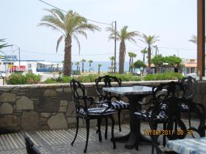 a table and chairs on a patio with palm trees at Kokalakis Hotel in Kefalos