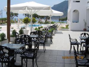 an outdoor patio with tables and chairs and a pool at Kokalakis Hotel in Kefalos
