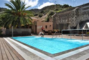 a swimming pool with a palm tree next to a building at Hotel Rural El Mondalón in Las Palmas de Gran Canaria