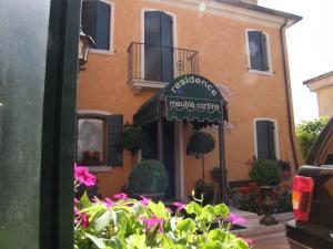 a building with a sign in front of a building with flowers at Residence Meuble' Cortina in Quinto di Treviso