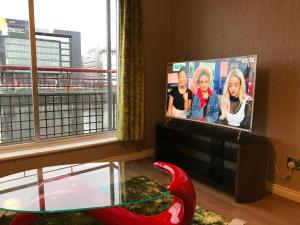 a living room with a tv and a glass table at Glasgow City Centre Flat with River Views and Parking in Glasgow
