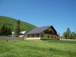 a yellow house with a black roof in a field at House Mara in Korenica