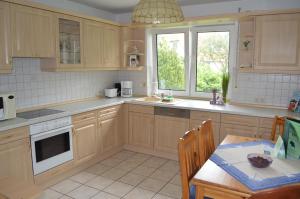 a kitchen with wooden cabinets and a table and a dining room at Twee Linden Nienhagen in Ostseebad Nienhagen