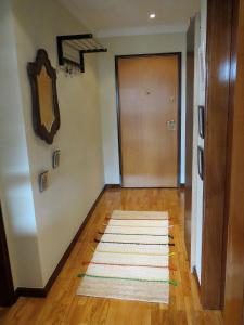 a hallway with a door and a rug on a wooden floor at Porto 1 Bedroom Beach Apartment in Matosinhos