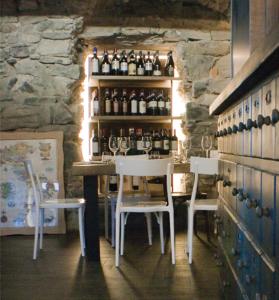 - un bar avec 2 chaises et une table avec des bouteilles de vin dans l'établissement Locanda Posta, à Argegno