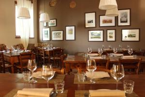 un restaurante con mesas de madera, sillas y copas de vino en Agriturismo Cascina Magana, en Burago di Molgora