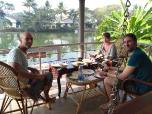 a group of three people sitting around a table at Mango Kerala Homes in Kumarakom