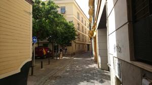 an empty alley way with buildings and trees on a street at Moratin Apartment in Seville