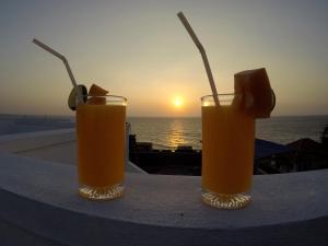 two glasses of orange juice sitting on a table with the sunset at Colombo Residency in Colombo
