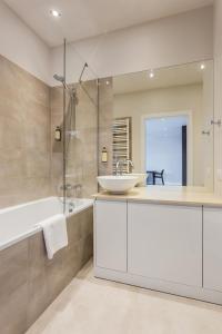 a bathroom with a tub, sink and mirror at Platinum Residence Mokotów in Warsaw