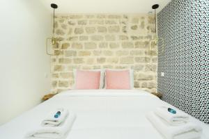 - un lit avec 2 oreillers roses et un mur en briques dans l'établissement Rent a Room - Charon 3, à Paris