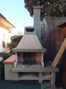 a outdoor oven sitting on a patio next to a fence at Villa Etrusca in Marina di Campo