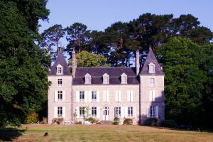 an old house on a field with trees at Château de Penfrat in Gouesnach