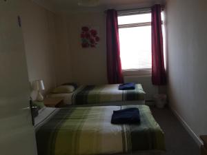 um quarto de hotel com duas camas e uma janela em Laughing Buddha Guesthouse em Uddingston