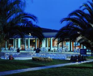 a building with chairs and tables and palm trees at Novotel Porto Gaia in Vila Nova de Gaia
