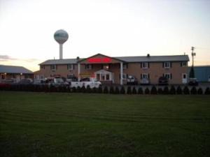 a building with a water tower in front of a field at Royal Inn Motel in Watertown