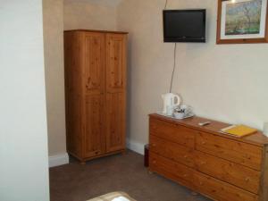 a bedroom with a wooden dresser and a tv on the wall at The Almar in Scarborough