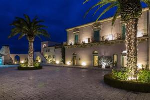 a building with palm trees in front of it at Poggio Del Sole Hotel in Contrada Cimillà