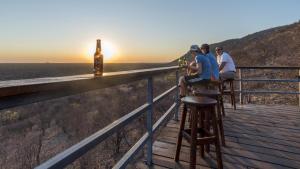 a group of people sitting at a bar watching the sunset at Gondwana Damara Mopane Lodge in Mopane Pos