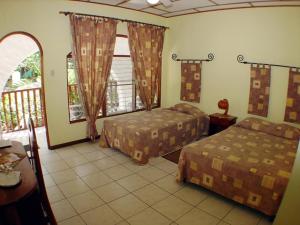 a hotel room with two beds and a balcony at Hotel Villa Romantica in Manuel Antonio