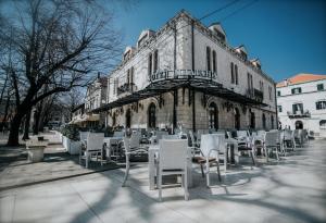 um grupo de cadeiras brancas em frente a um edifício em Hotel Platani em Trebinje