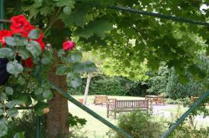 a park with two benches and a tree with red roses at Ardboyne Hotel in Navan