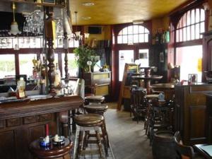 a restaurant with a bar and stools in a room at The Pipers in Middelkerke