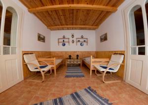 a living room with wooden ceilings and chairs and a table at Hauszmann Vendégház in Palotabozsok