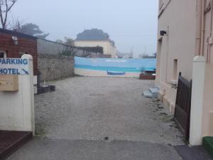 a parking lot next to a building with a blue wall at Hotel de la Plage in Quinéville
