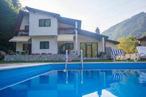 a villa with a swimming pool in front of a house at Casuta Didi in Brezoi