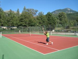 a person hitting a tennis ball on a tennis court at Camping Les Grillons in Embrun