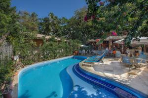 a swimming pool with chairs and tables in a resort at Pousada Ogum Marinho in Praia do Forte