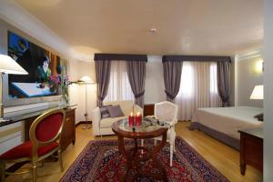 ヴェネツィアにあるホテル リアッシディ パレスのベッドとテーブル付きのホテルルームとベッドルーム1室が備わります。