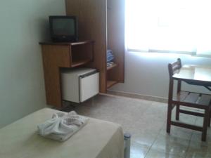 a room with a bed and a table and a television at Hotel Columbia Palace in Pirassununga