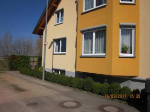 a yellow house with white windows on a street at Luba Rube in Rust