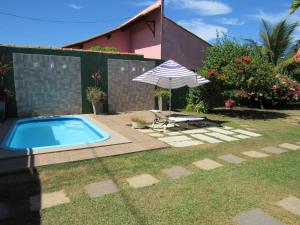 einen Pool mit einem Sonnenschirm, einem Stuhl, einem Tisch und einem Sonnenschirm in der Unterkunft Pousada Mangas in Manguinhos