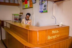 a man standing at the counter of a hotel restaurant at Sunshine Hotel Tengecha in Kericho