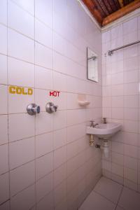 Baño de azulejos blancos con lavabo y aseo en Sunshine Hotel Tengecha, en Kericho
