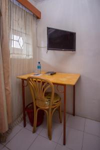 mesa de madera con silla y TV en la pared en Sunshine Hotel Tengecha, en Kericho