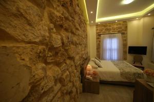 ein Schlafzimmer mit einer Steinwand, in dem ein Bett und ein Fernseher stehen. in der Unterkunft Asamina Boutique Hotel in Tyros
