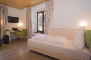 Schlafzimmer mit einem Bett, einem Schreibtisch und einem Fenster in der Unterkunft Hotel-Restaurant Bibermühle GmbH in Tengen