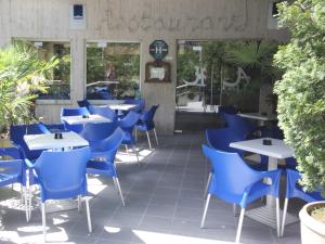 a restaurant with blue chairs and tables on a patio at Hôtel Atlantic in Lourdes