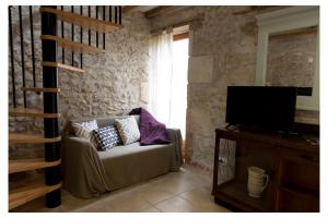 ein Wohnzimmer mit einem Sofa und einem TV in der Unterkunft Domaine de la Grange aux Dîmes in Feux