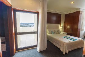a bedroom with a bed and a large window at Hotel Eurosol Leiria & Jardim in Leiria